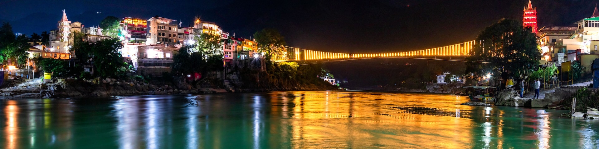 A river at night with a bridge and illuminated buildings on the opposite bank.