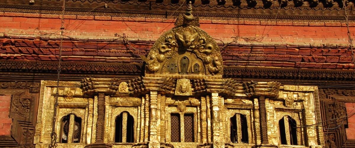 A detailed architectural facade with ornate carvings and golden accents.