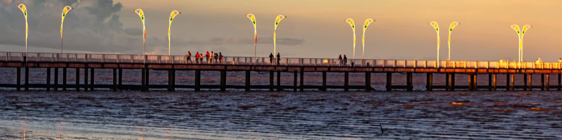 Un muelle se adentra en un cuerpo de agua bajo un cielo de atardecer.