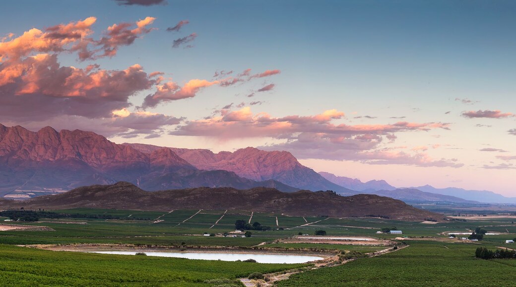 A mountainous landscape with a valley, green fields, and a small body of water.