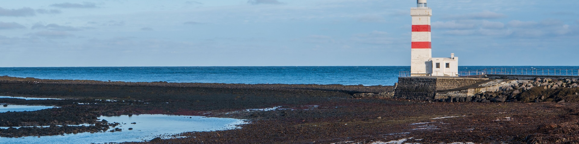 Un phare sur une côte rocheuse, avec la mer en arrière-plan.