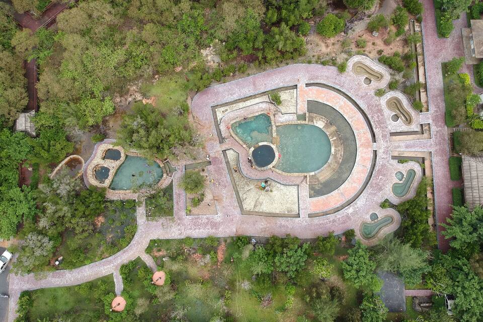 An aerial view of a park with multiple ponds, walking paths, and surrounding greenery.