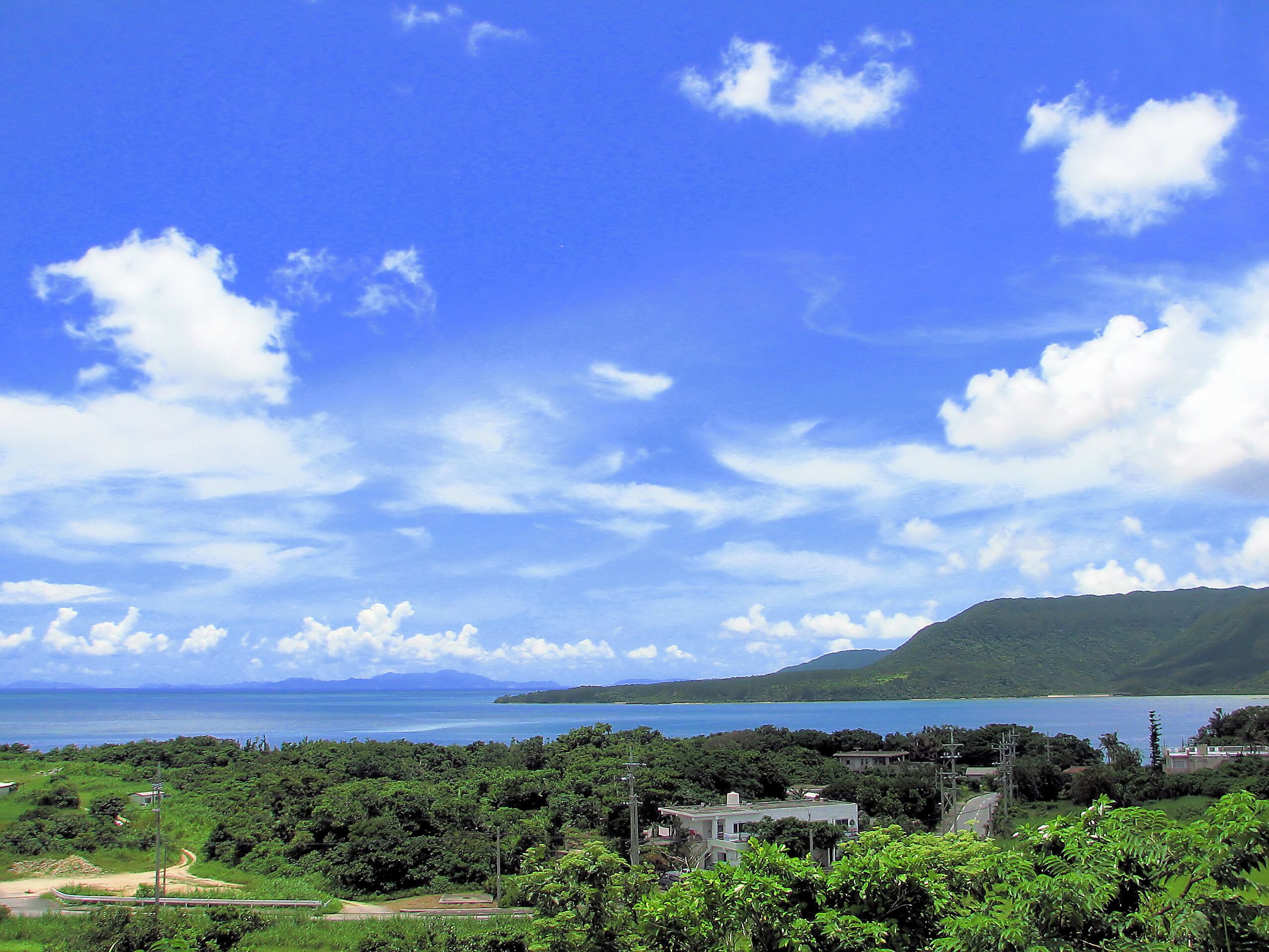 A coastal landscape with a clear sky, a body of water, and green hills.
