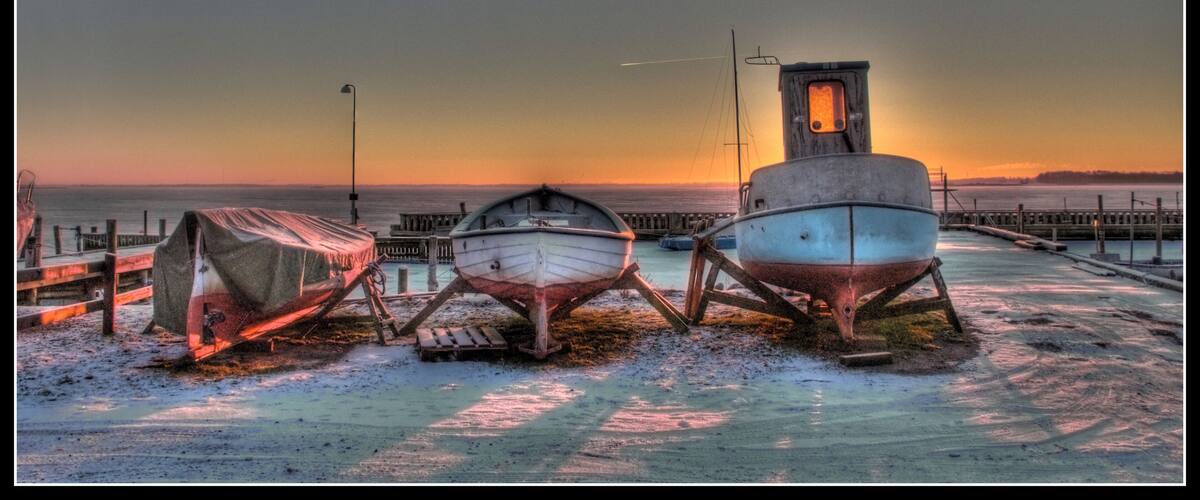 Three boats on a dock with a sunset in the background.