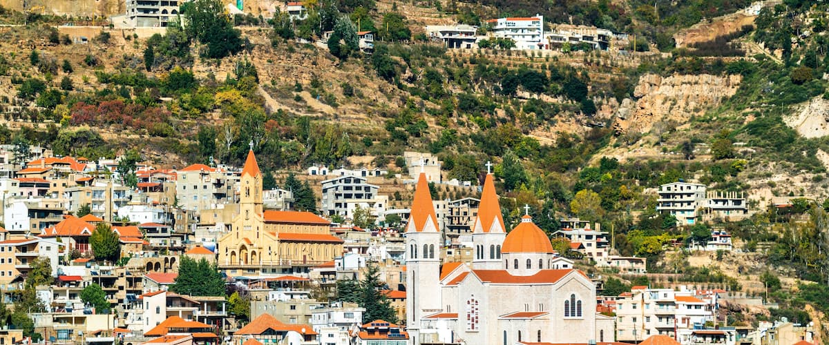 A densely packed hillside town with numerous buildings, including a prominent church with two tall spires and a smaller church with a single spire.