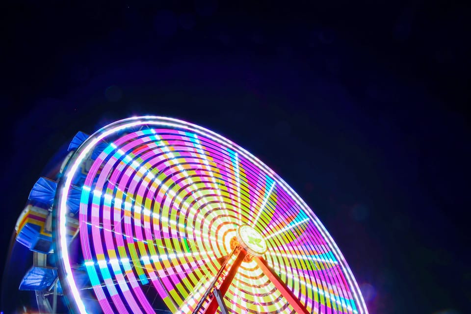 A brightly lit Ferris wheel with colorful lights against a dark night sky.