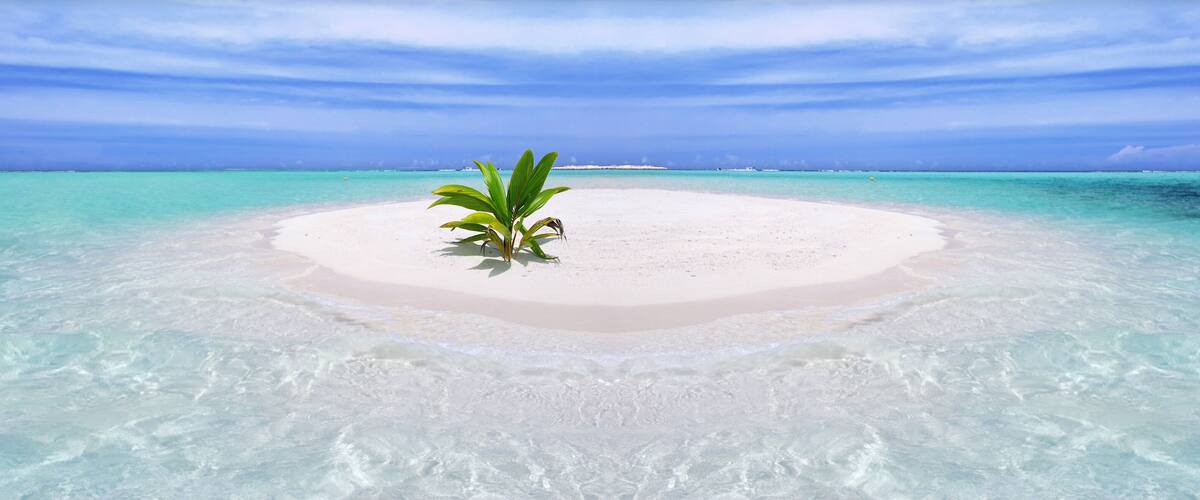 A small island with clear turquoise waters and a sandy beach.