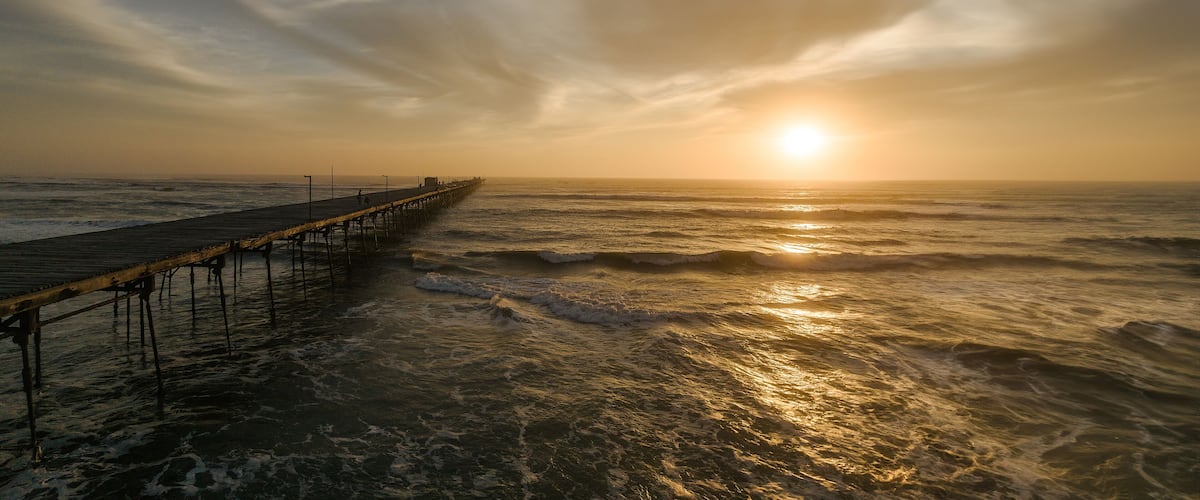Pier in the ocean on a colorful sunset. Puerto Eten.