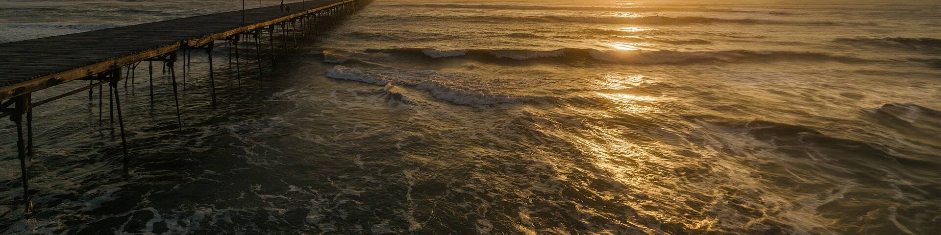 Pier in the ocean on a colorful sunset. Puerto Eten.