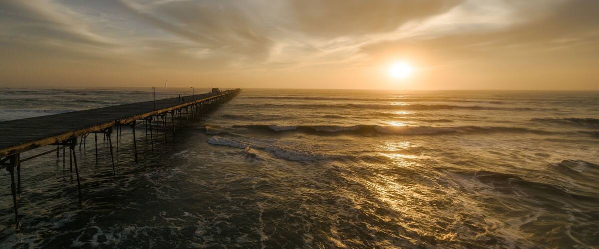 A pier extending into the ocean at sunset.