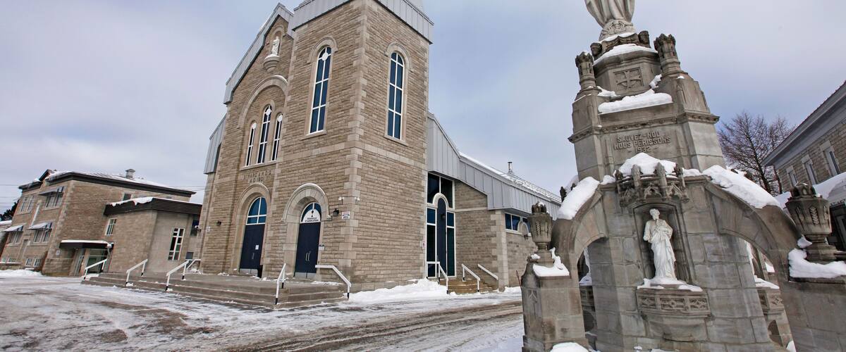 A church with a steeple and a statue of a figure with outstretched arms.