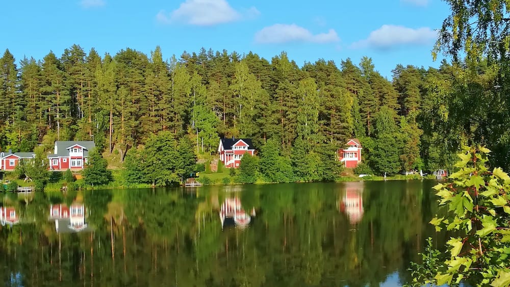Un lac paisible, bordé de maisons rouges et entouré d’une forêt dense.