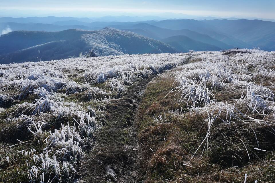 A frost-covered mountainous landscape with a clear sky.