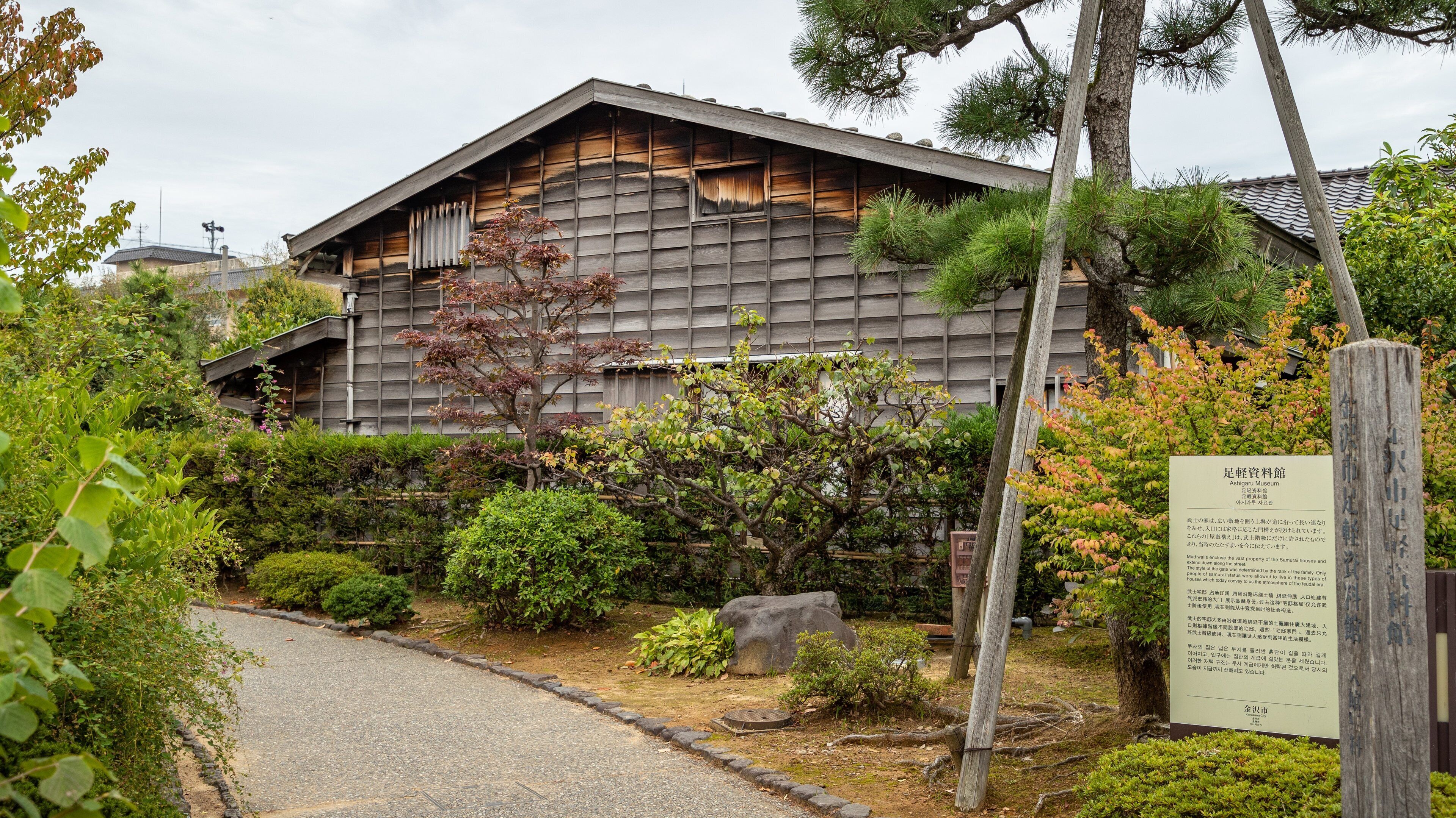 A traditional Japanese building surrounded by lush greenery and a stone pathway.