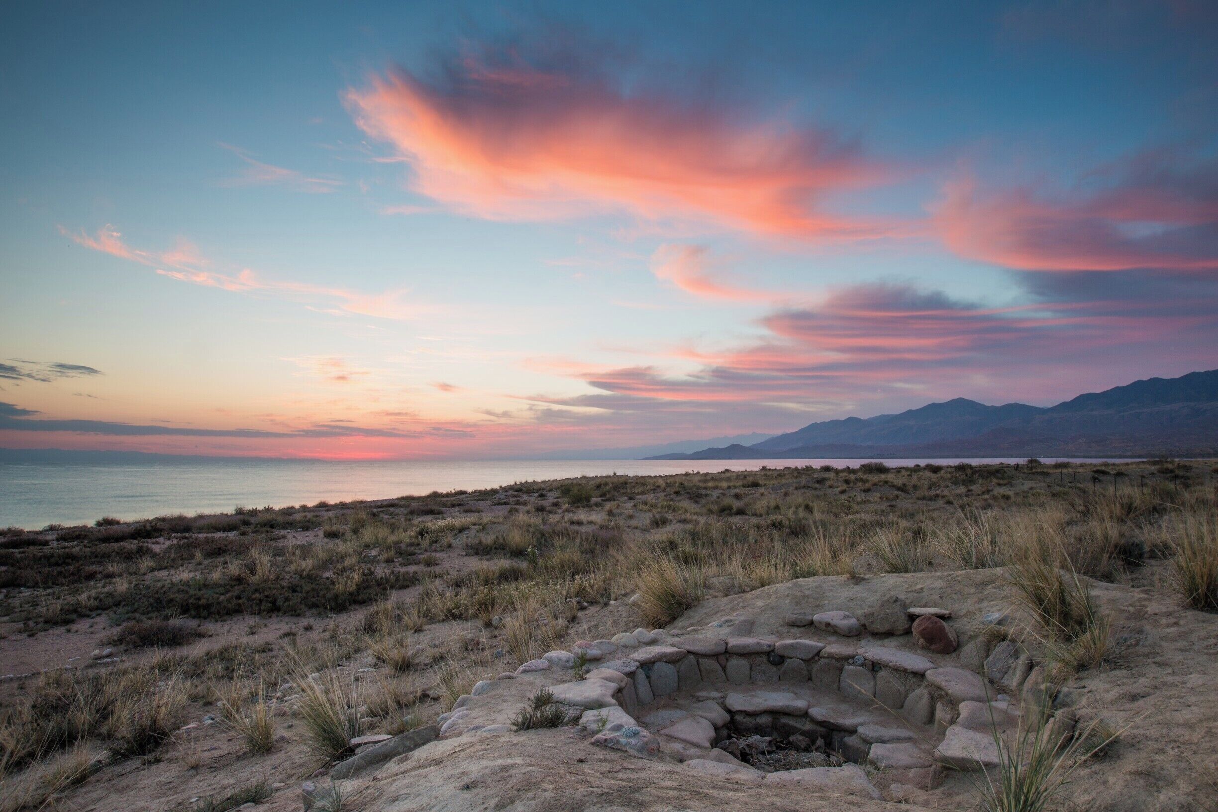 A sunset over a desert landscape with a stone structure in the foreground.