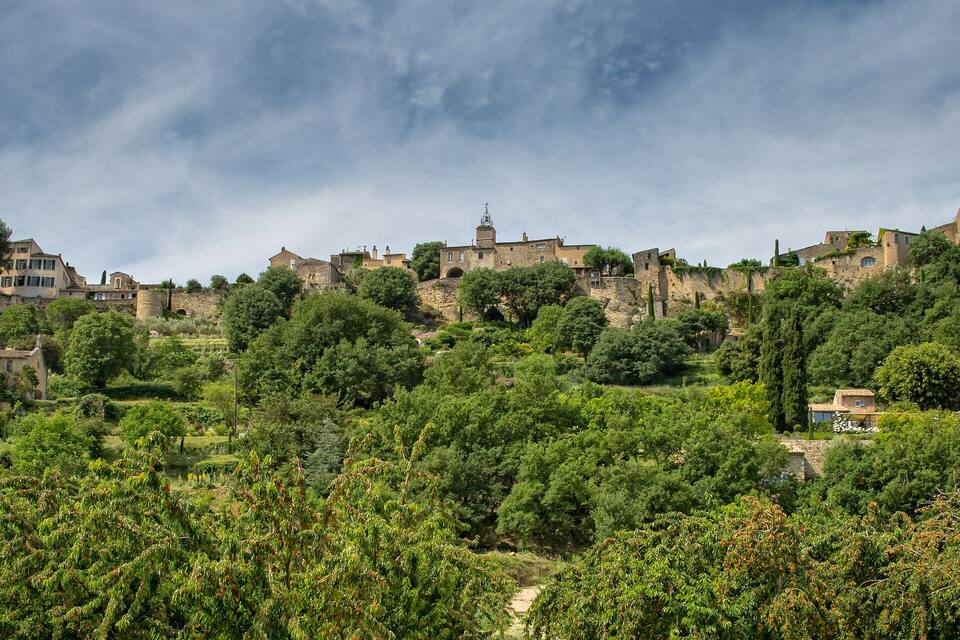 A hillside village with historic stone buildings and lush greenery.