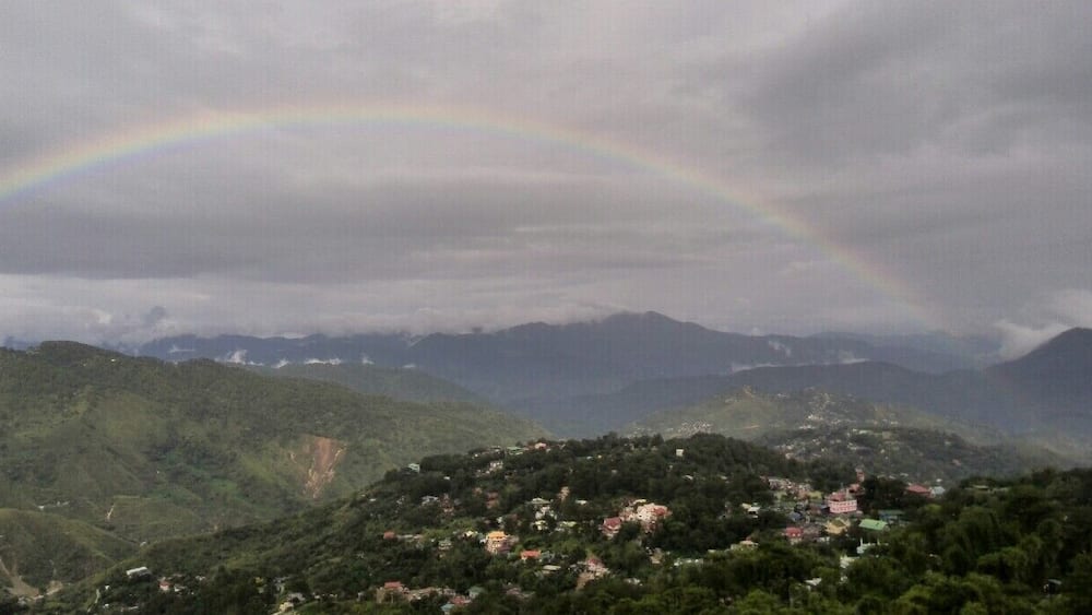 Un paysage de montagne avec un arc-en-ciel au-dessus d’un village.