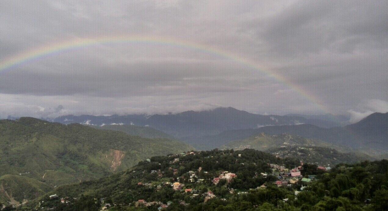 A mountain landscape with a rainbow over a village.
