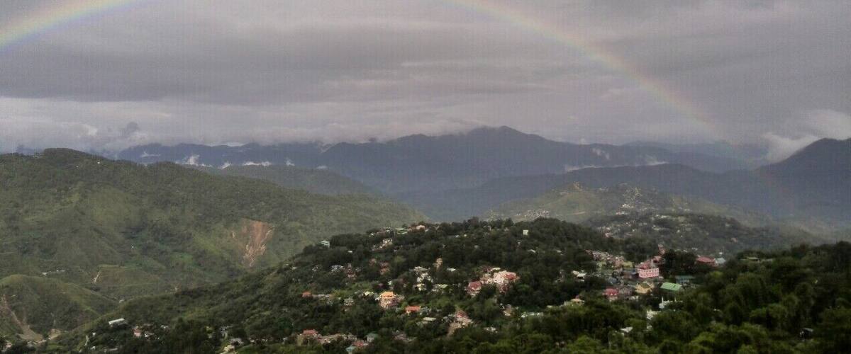 A mountain landscape with a rainbow over a village.