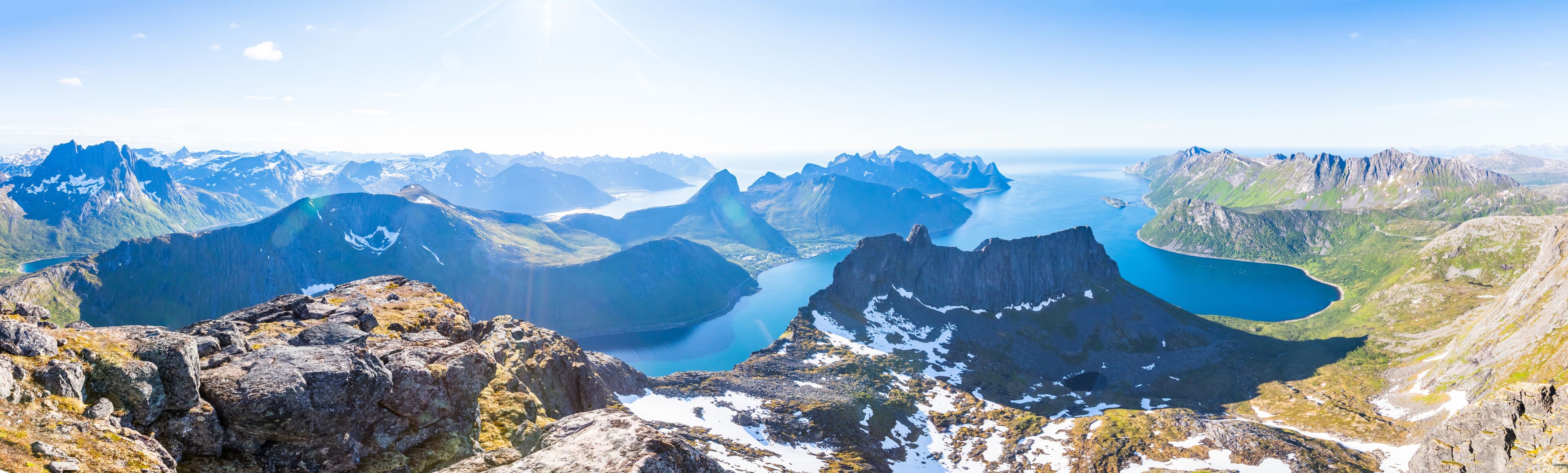Un paysage montagneux aux pics escarpés, un lac d’un bleu profond et un ciel dégagé.