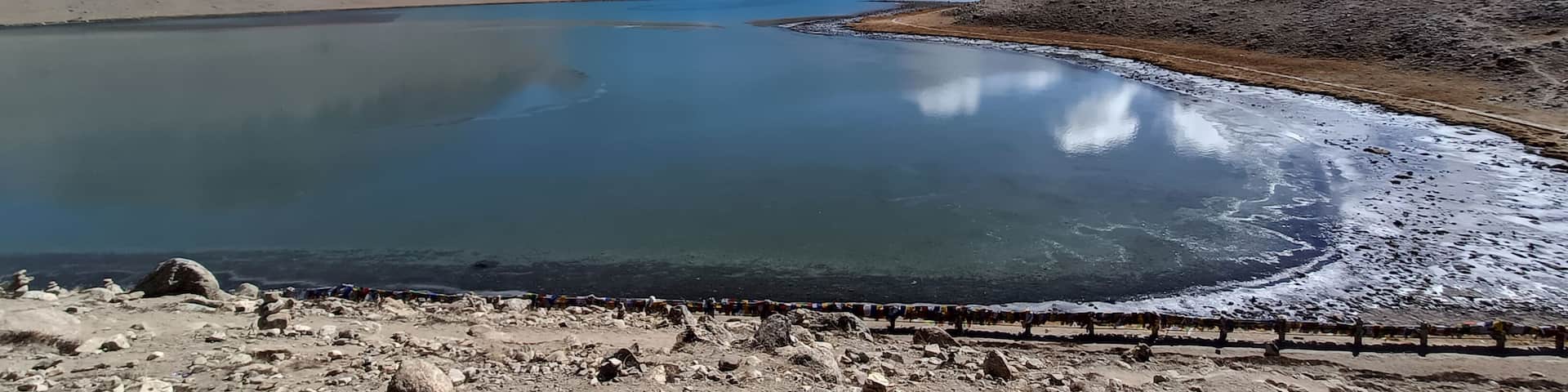 A serene lake surrounded by mountains with a clear sky.
