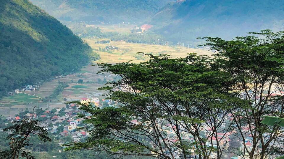 A valley with a town nestled among green hills and mountains.