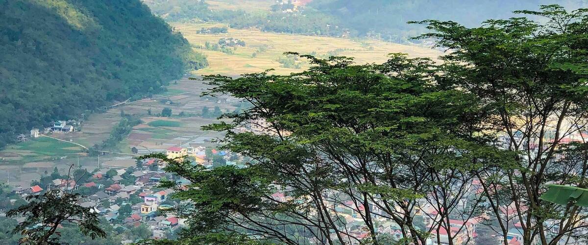 A valley with a town nestled among green hills and mountains.