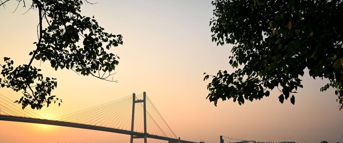 A sunset over a river with a bridge and boats.
