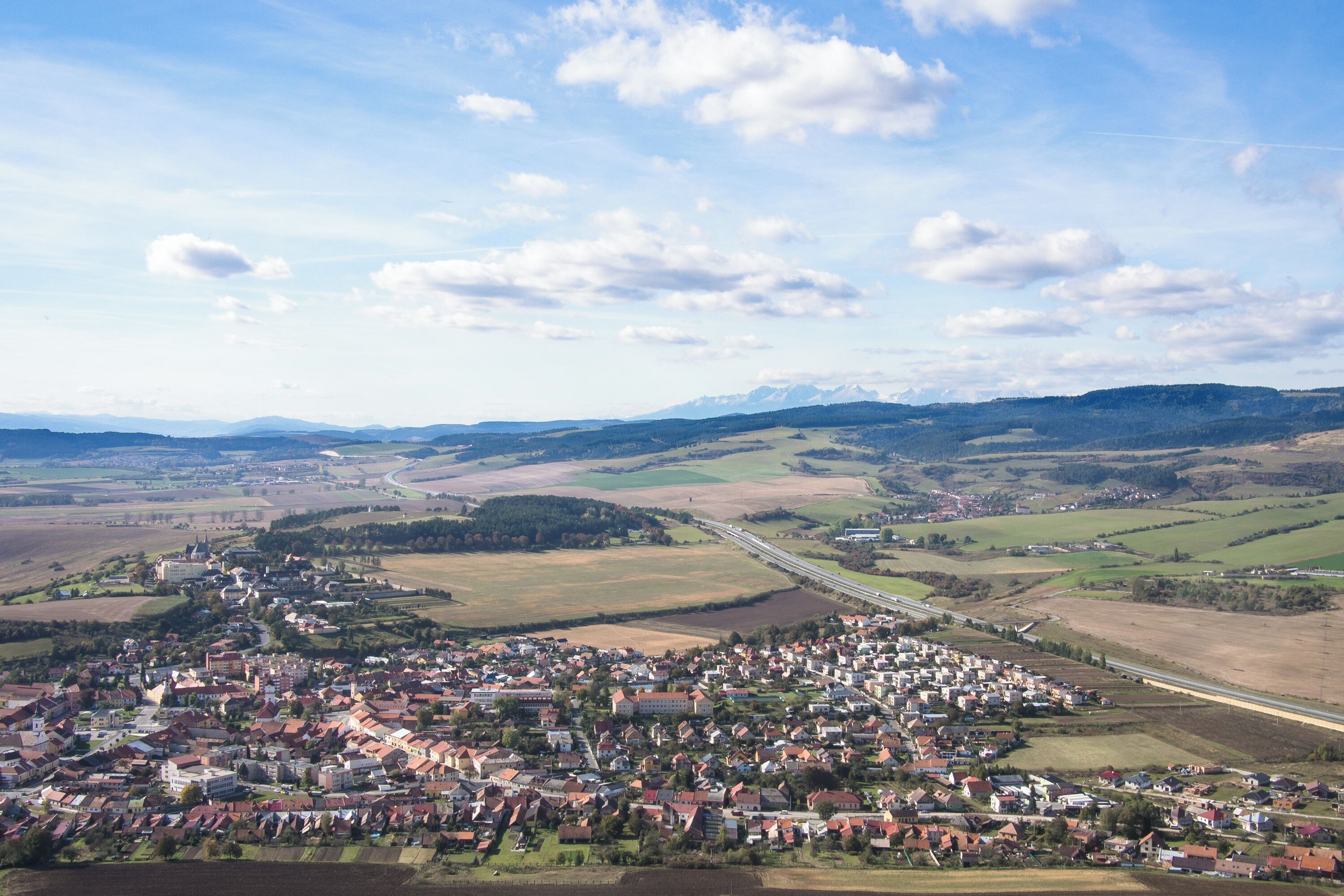 A town nestled in a valley with a river, surrounded by fields and mountains.