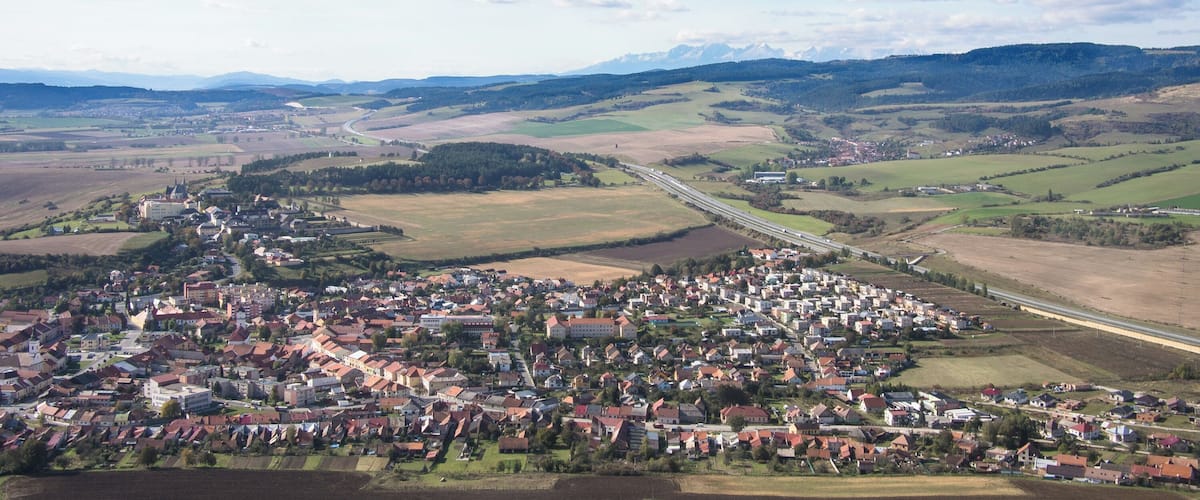 A town nestled in a valley with a river, surrounded by fields and mountains.