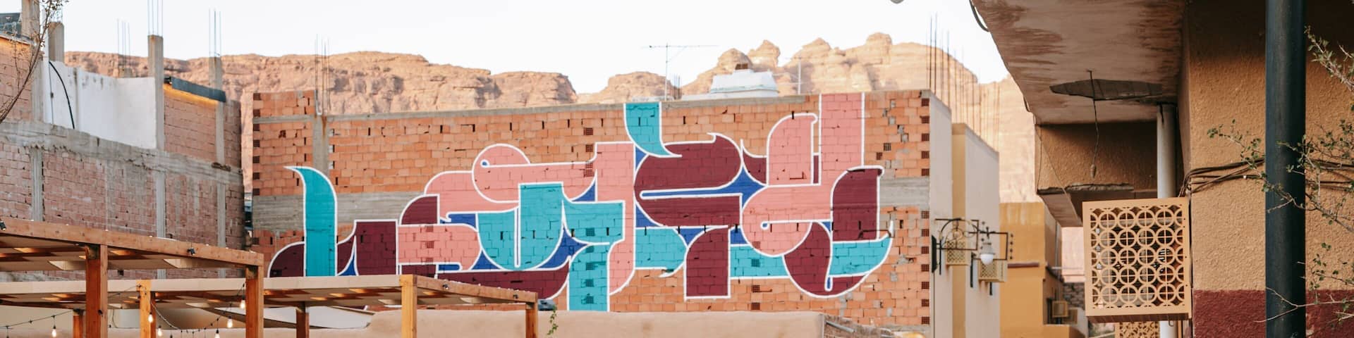 A man walking on a paved street with a colorful mural in the background.