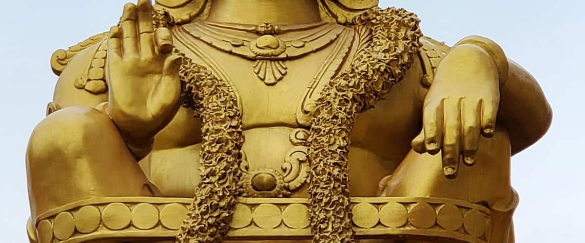A golden statue of a deity with intricate jewelry and a traditional headdress.