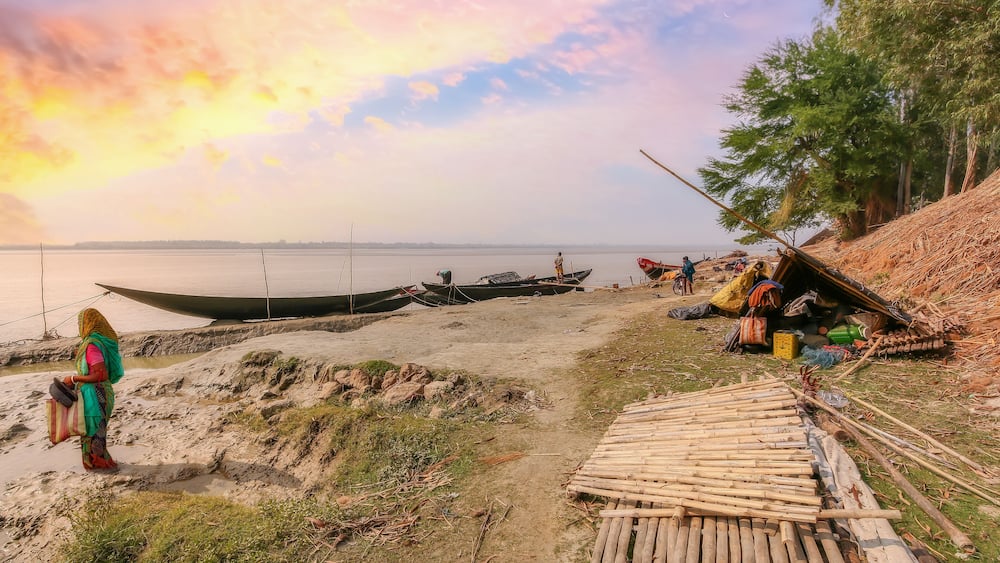 Rupnarayan river bank at sunset with view of fishing boats and rural village people at Deulti, West Bengal, India.