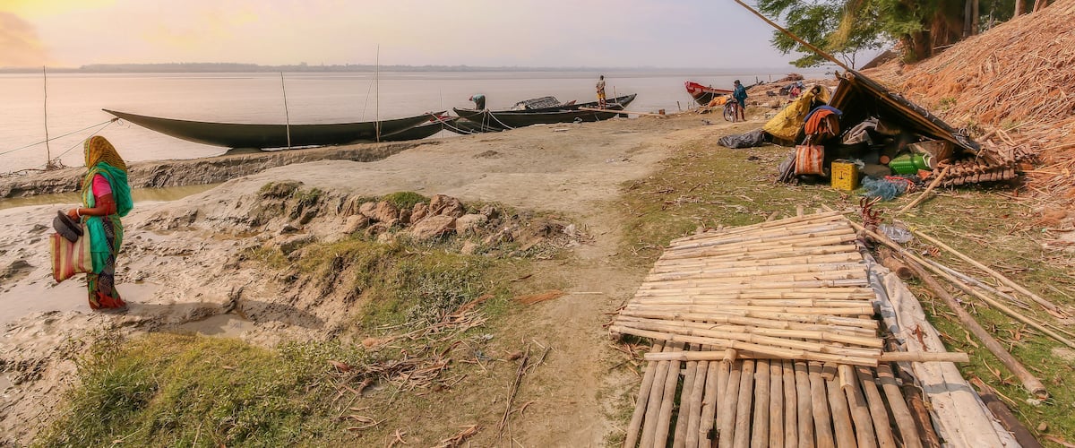 Rupnarayan river bank at sunset with view of fishing boats and rural village people at Deulti, West Bengal, India.