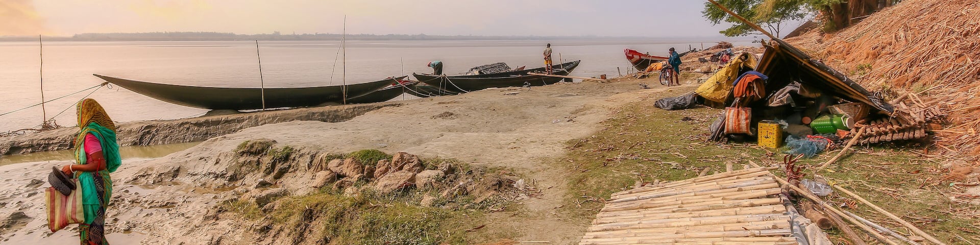 Rupnarayan river bank at sunset with view of fishing boats and rural village people at Deulti, West Bengal, India.