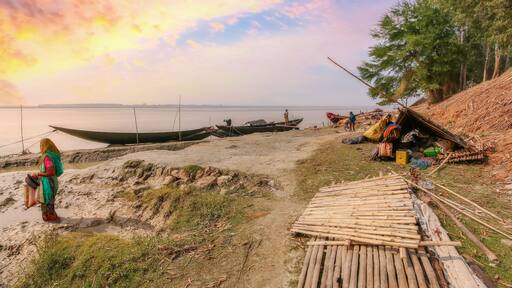 Rupnarayan river bank at sunset with view of fishing boats and rural village people at Deulti, West Bengal, India.