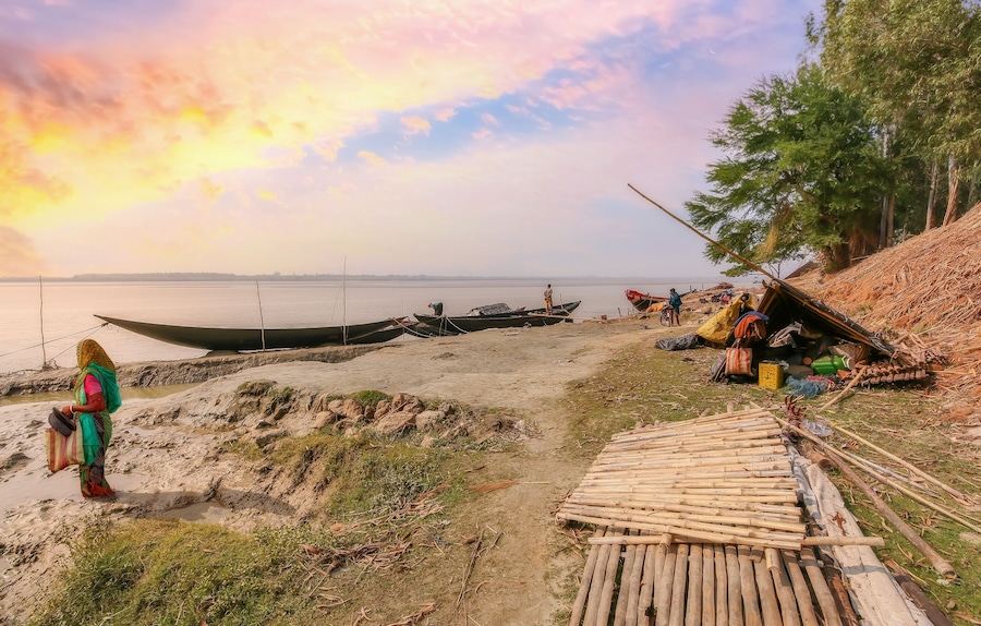 Rupnarayan river bank at sunset with view of fishing boats and rural village people at Deulti, West Bengal, India.