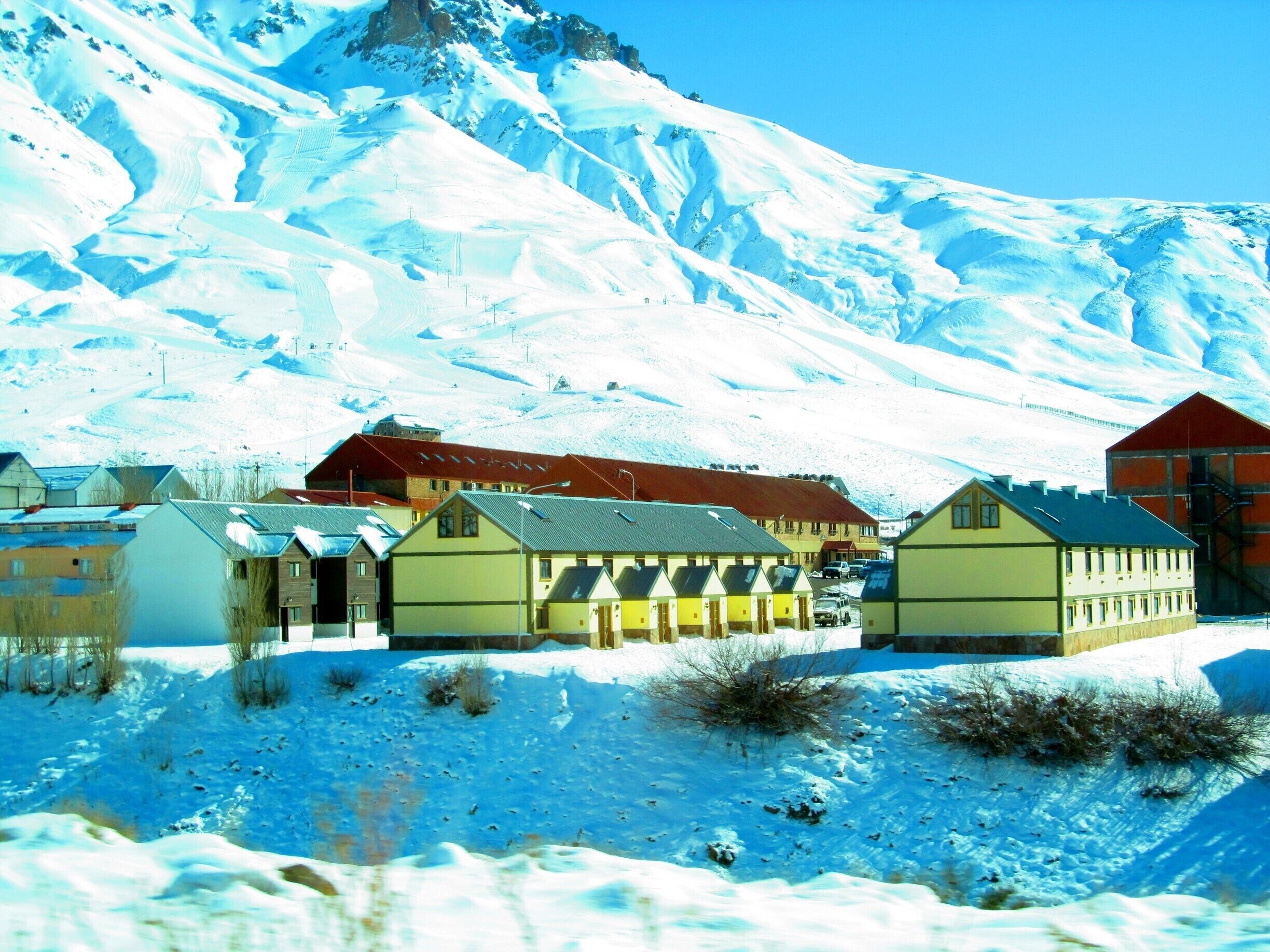 A snow-covered village with buildings and a mountain in the background.