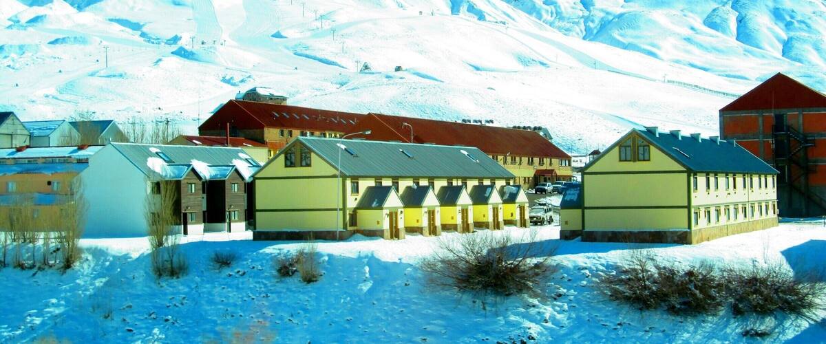 A snow-covered village with buildings and a mountain in the background.