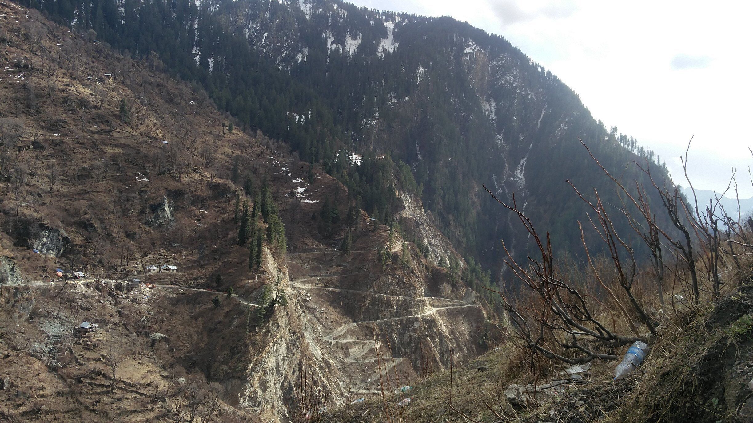 A mountainous landscape with a winding road, rocky terrain, and sparse vegetation.