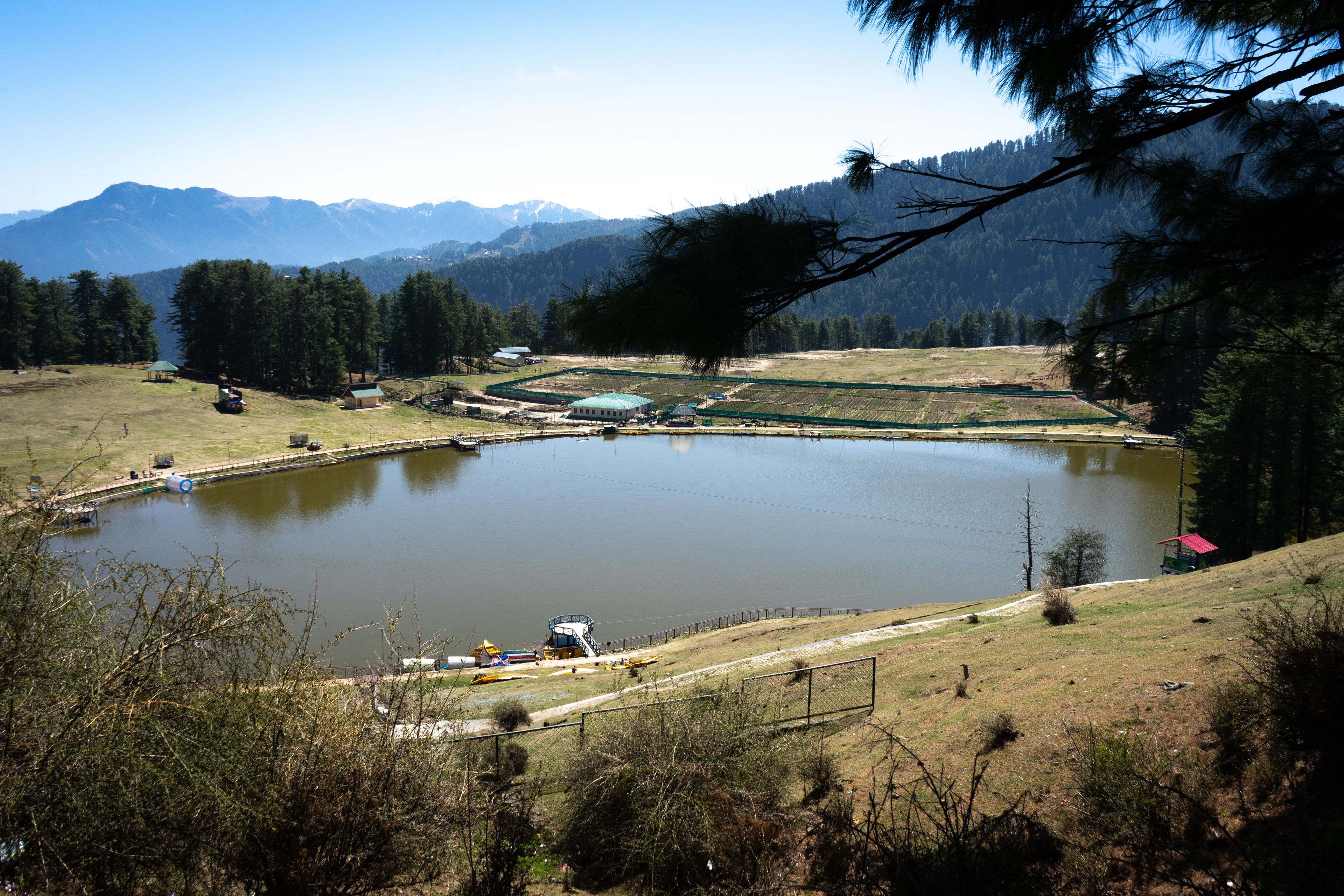 Un lac entouré de montagnes, un petit quai et quelques bâtiments.