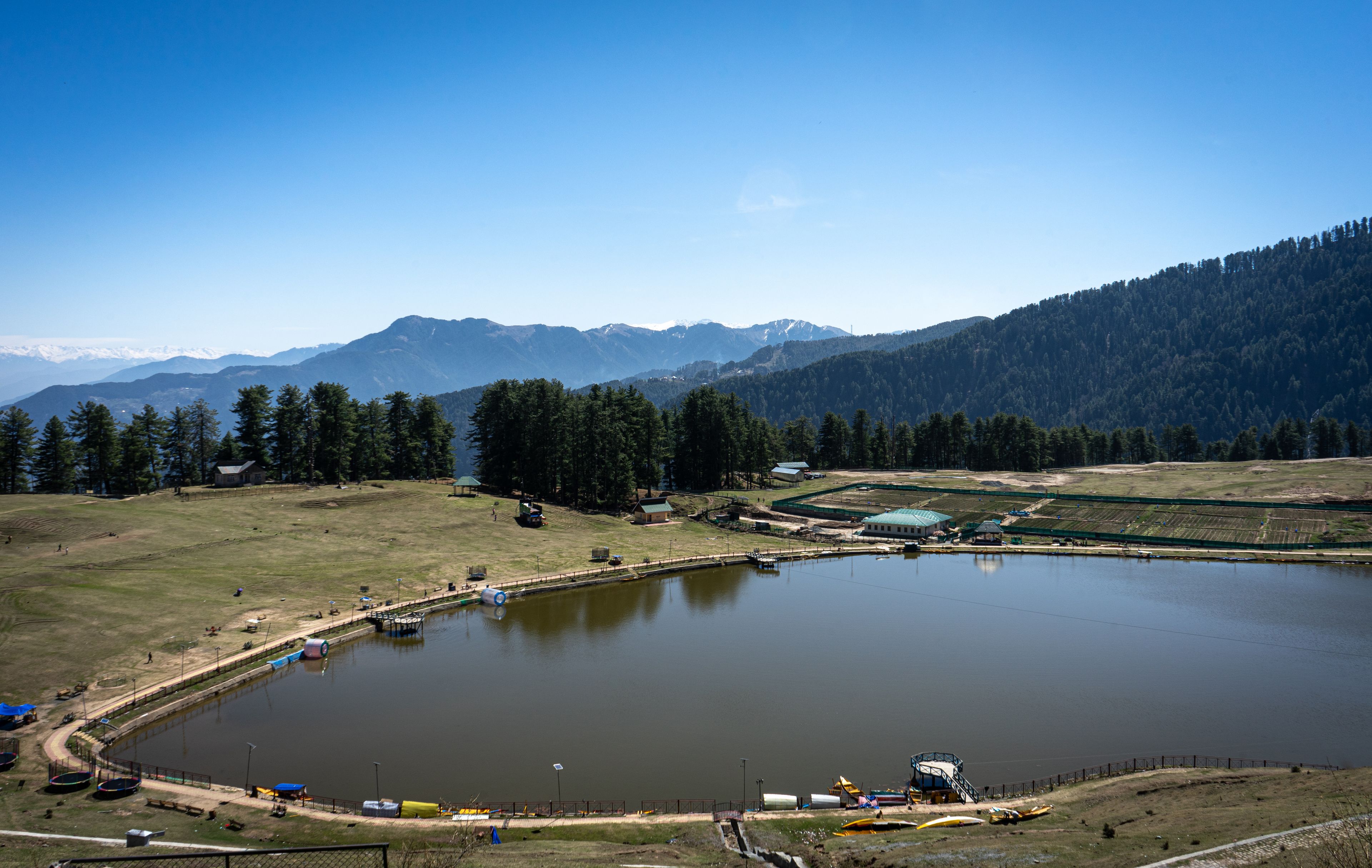 Un grand lac entouré de montagnes, un petit village avec quelques bâtiments et une zone boisée.