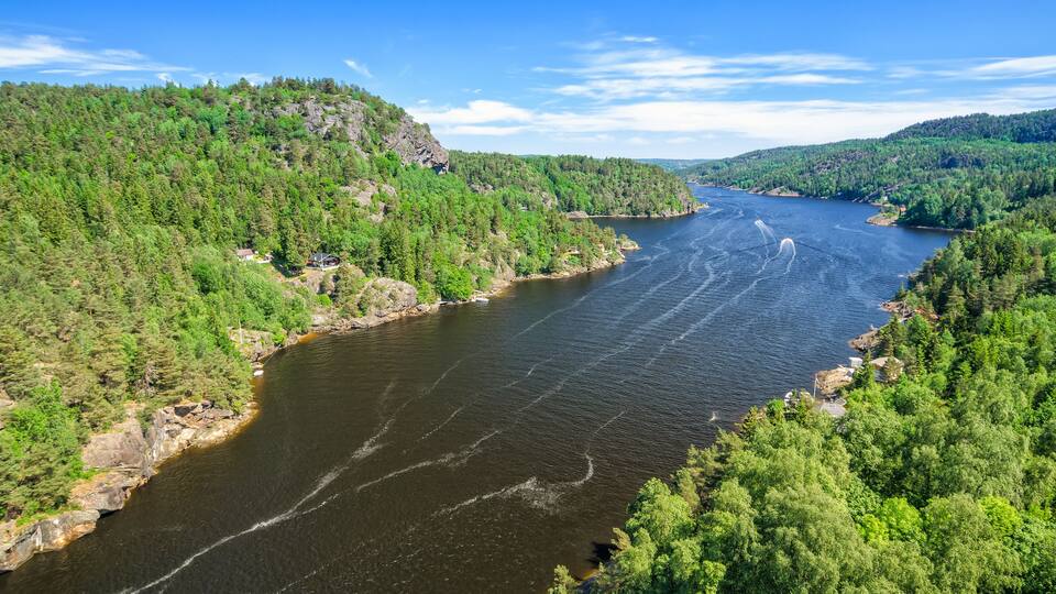 A river winding through a densely forested valley with rocky outcrops and a clear blue sky.
