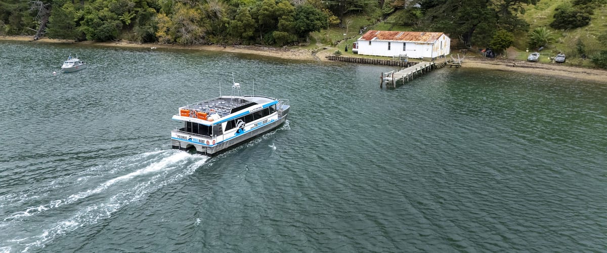 A boat on a calm river with a dock and a house in the background.