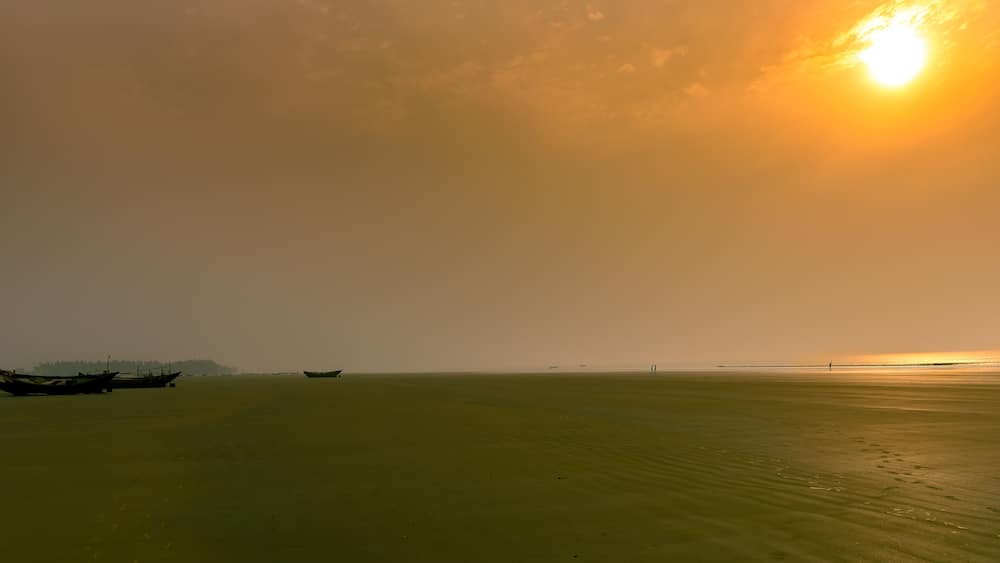 A calm sea with boats and a distant shoreline.