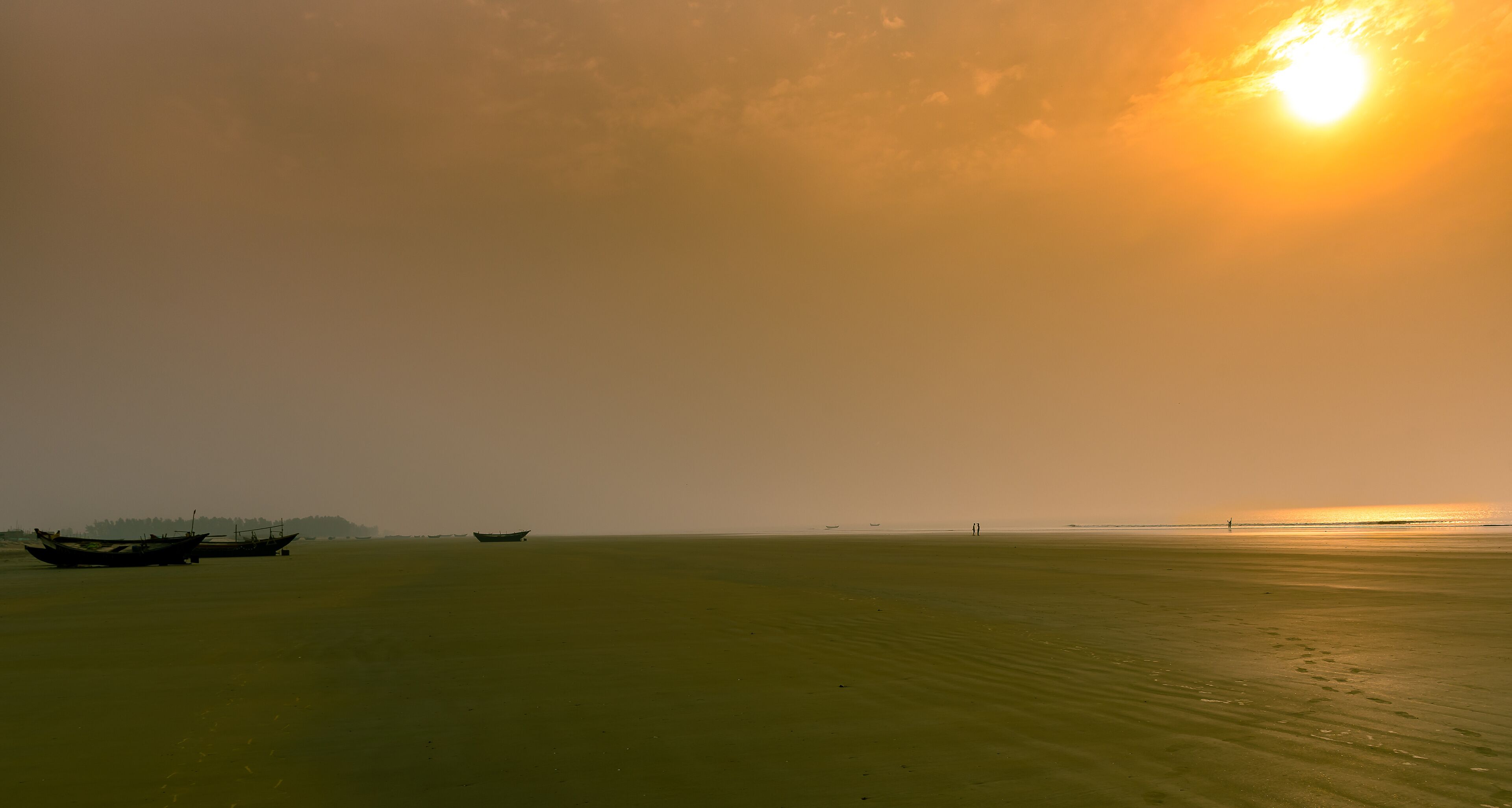 A calm sea with boats and a distant shoreline.