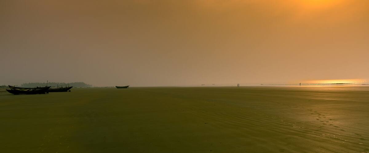 A calm sea with boats and a distant shoreline.