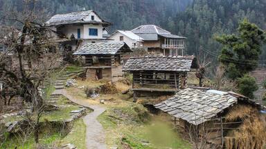 A rural village with traditional houses, a stone path, and a mountainous backdrop.
