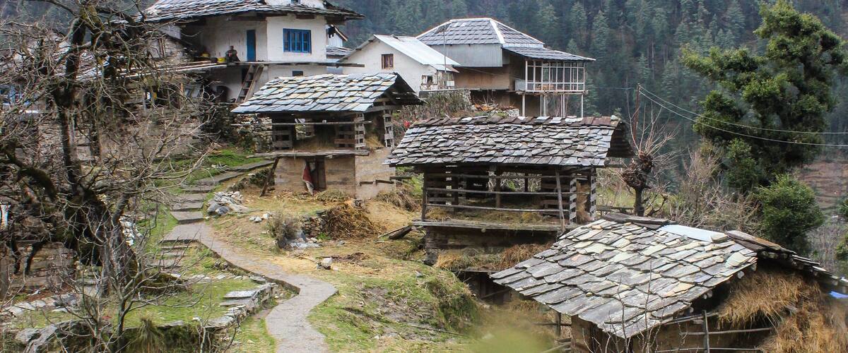 A rural village with traditional houses, a stone path, and a mountainous backdrop.