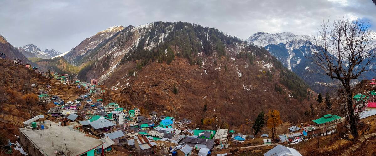 A mountainous village with colorful houses and snow-capped peaks in the background.